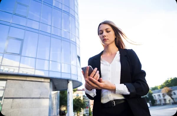 Profissional usando smartphone em frente a edifício corporativo moderno